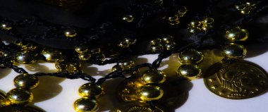 Altın paraların ve boncukların bulanıklığı sanatsal olarak koyu kumaşa örtülmüş. Karmaşık bir desen oluşturuyor. Parlak altın elementler, savurgan bir görünüm için koyu kumaşla çok güzel tezat oluşturuyor.