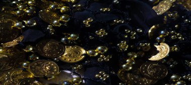 Karmaşık bir şekilde tasarlanmış, altın para ve boncuklarla süslenmiş siyah kumaş bulanıklığı. Işığı çeşitli yönlere yansıtıyor. Bu canlı kumaş, lüks bir dokunuşla karmaşık bir desen sergiliyor..