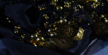 Koyu kumaş üzerine sanatsal katmanlı altın sikke ve boncukların bulanıklığı lüks ve zarif bir doku yaratıyor. Bu kumaş karmaşık bir tasarımla üst düzey cazibe yayar.