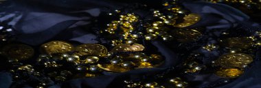 Altın boncuklar ve sikkelerle süslenmiş güzel bir kumaş, zengin, lüks bir doku sunuyor ve koyu ve parlak renklerle detaylandırılmış zarif bir detay..