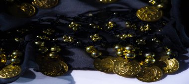 Karmaşık siyah kumaş, altın boncuklar ve sikkelerle süslenmiş zarafet ve zenginlik saçan güzel desenli ve süslü bir görünüme sahip..