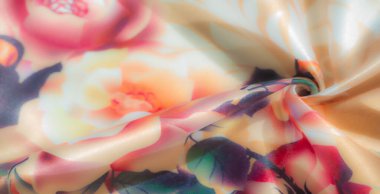 Görüntü. Yeşil ve koyu mor yapraklarla eşleştirilmiş, ılık turuncu ve soluk pembe güllerle güzel bir çiçek aranjmanı. Bu yumuşak ve canlı tasarım, tekstil zarafetine bir dokunuş ekler.