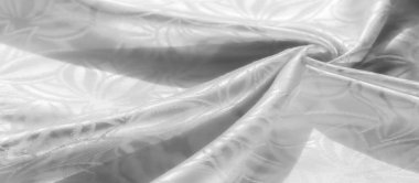 Beyaz saten kumaş üzerinde güzel detaylandırılmış soyut tasarım. Yüksek çözünürlüklü yakın çekim tekstilin pürüzsüzlüğünü ve lüks kalitesini ön plana çıkararak moda ve dekor için ideal hale getiriyor.,