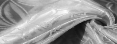 Beyaz saten kumaş üzerinde güzel detaylandırılmış soyut tasarım. Yüksek çözünürlüklü yakın çekim tekstilin pürüzsüzlüğünü ve lüks kalitesini ön plana çıkararak moda ve dekor için ideal hale getiriyor.,