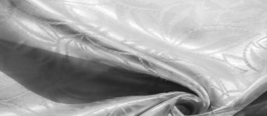 İnce yaprak motifli beyaz saten kumaşın yakın görüntüsü. Yumuşak, pürüzsüz dokusu arka planlar, iç tasarım projeleri ve moda uygulamaları için mükemmeldir.