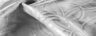 Karmaşık geometrik desenlere sahip düz beyaz saten kumaşın detaylı bir yakın çekimi. Doku lüks ve ipeklidir. Zarif kıvrımlar yaratır ve arka plan veya tekstil tasarımı için idealdir.