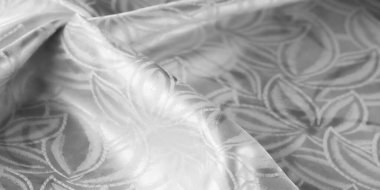 Ayrıntılı çiçek desenleri ve kırışıklıkları olan parlak beyaz kumaş.