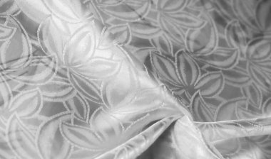 Beyaz saten kumaş üzerinde çarpıcı bir şablon, pürüzsüz dokuları ve ince detayları yakından gösteriyor. Arkaplanda, moda tasarımında veya iç dekorasyon projelerinde kullanım için ideal