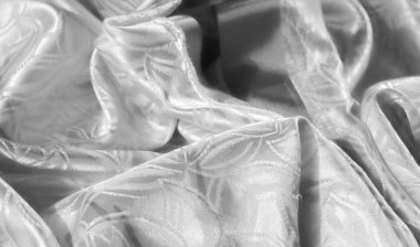 Yaprak motifli parlak beyaz kumaş. Zarif ışıklandırmada karmaşık desenler ve yumuşak doku sergiliyor.