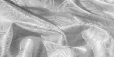 Karmaşık kabartmalı desenli beyaz saten kumaş, pürüzsüz doku ve yumuşak kıvrımlar sergiliyor. Kumaş ışığı yansıtıyor, zarif çiçek ve yaprak tasarımlarını ince bir şekilde vurguluyor.