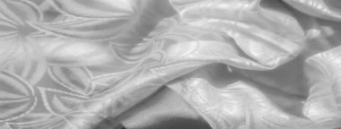 Ayrıntılı, lüks, karmaşık dokuma desenleri ve ince bir çiçek motifi olan beyaz saten kumaşın yakın plan görüntüsü. İpeksi dokusu yumuşak ışığı yansıtıyor, zarif ve eğri tasarımları geliştiriyor..