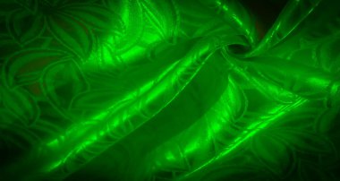 Karmaşık yaprak desenleri olan parlak yeşil bir kumaşın detaylı görüntüsü dinamik kıvrımlar ve açık gölgeler halinde materyalin yumuşak parıltısını yakalıyor..