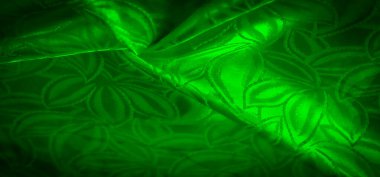 Canlı, dokulu, karmaşık, yaprak benzeri desenleri olan yeşil bir kumaş. Kumaş, koyu yeşil bir tonu ve organik şekilleriyle zengin ve ipeksi görünüyor.