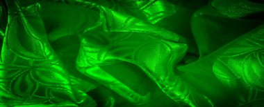 Yapraklı kabartma desenli canlı yeşil ipek kumaş. Kumaş nazikçe örtülmüş, yumuşak gölgeler ve gölgeler yaratıyor..