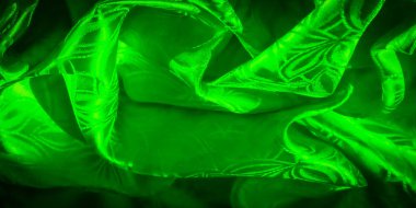 Canlı yeşil, parlak bir kumaş. Karmaşık bir yaprak gibi, akan bir desen. Kumaş ışığı yansıtır, ipeksi, pürüzsüz ve lüks bir doku yaratır. Materyaldeki kıvrımlar boyutu arttırır.