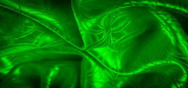 Yaprak benzeri karmaşık desenlere sahip yeşil saten bir kumaş. Işıkla aydınlatılmış. Yumuşak, akıcı bir doku yaratıyor..