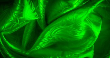 Parlak yeşil bir kumaş. Karmaşık yaprak desenleri var. Işıkla aydınlatılıyor..