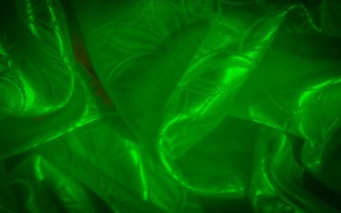 Karmaşık yaprak desenli kırışık yeşil saten bir kumaş. Doku ve derinliği ortaya çıkarmak için aydınlatılmış..