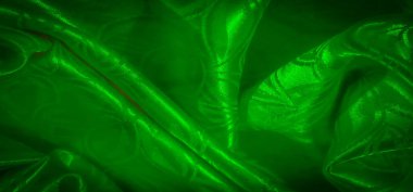 Hassas bir yaprak desenli karmaşık yeşil saten kumaş. Lüks ve ışıltılı bir doku yaratmak için nazikçe katlanmış. Işığı zarifçe yansıtıyor..