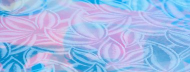 Pastel renkte buruşuk saten kumaş. Işığı yakalayan bir çiçek deseni var. Parlak ve narin bir görünüm veriyor..