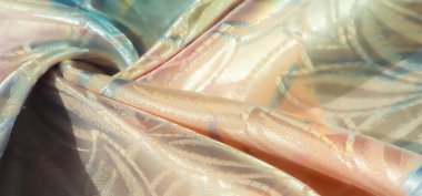 Pastel gölgeler ve kumaş üzerindeki çiçek desenlerinin birleşimi parlak ve yansıtıcı bir yüzey oluşturur. Kumaş özenle katlanır, pürüzsüz dokusu ve karmaşık tasarımı gözler önüne serilir..