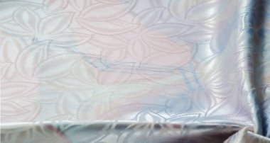 Yanardöner çiçek desenli yumuşak pastel kumaş, ışık ve gölge oyunu oynamak için nazikçe kırışmış..