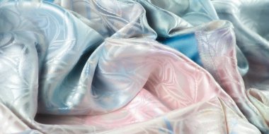 Pembe ve mavinin yumuşak tonlarıyla zarif bir kumaş. Karmaşık desenler doğal ışık altında parlıyor, tekstil lüks ve narin bir görünüme sahip..