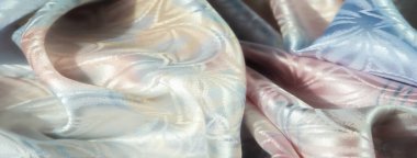 Katları akan lüks kumaşlar, içinde pastel çiçekli bir tasarım var. Yumuşak parıltı ve canlı renk paleti zarafet ve karmaşıklığı çağrıştırıyor..
