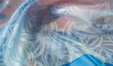 Yumuşak pastel renkli kumaş, çiçek desenli ve parlak bir kaplama. Nazik kıvrımlar ışık yansımaları yaratır ve yüzeye hassas bir doku ekler..