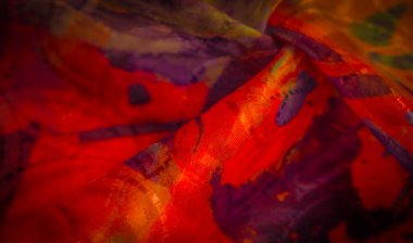 Kırmızılar, sarılar ve morlar gibi zengin dokulara sahip çok renkli kumaşlar karmaşık şekillerde katlanmış. Canlı renkler ve soyut tasarımlar bu dinamik yakın plan çekimde düzgün bir şekilde harmanlanır..