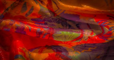 Mor soyut desenli turuncu, sarı ve kırmızı kumaştan parlak kıvrımlar, ışık yansımaları ile vurgulanmış..