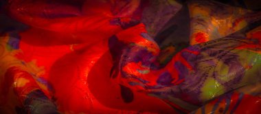 Girdap desenli canlı bir kumaş yakın plan, zengin kırmızı, turuncu ve mor renkler sergiliyor yumuşak, desenli parıltılı.