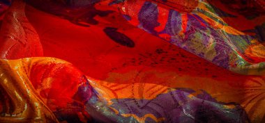 Renkli, kırmızı, turuncu ve sarı tonlarda kumaş, çarpıcı bir renk akışı ve parlak bir bitiş..