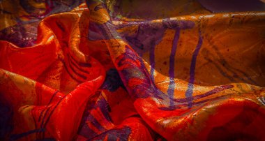 Parlak turuncu, kırmızı ve sarı tonlarıyla canlı, soyut bir kumaş dinamik, sanatsal bir akış ve doku yaratır..