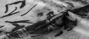 Bu görüntü, kumaşın akış hareketini siyah soyut bir desenle yakalar. Yumuşak doku ve katmanlı kıvrımlar ışık ve gölgenin zengin bir etkileşimini yaratır..