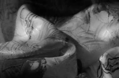 Karmaşık desenleri olan yumuşak ve akışkan bir kumaş. Siyah ve beyaz kompozisyon dokuyu ve ince kıvrımları vurgular..