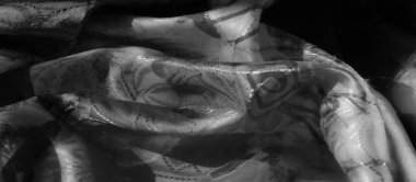 Yumuşak desenli ve arka planda dokuları olan bir kumaş üzerindeki soyut siyah fırça darbelerinin yakın çekimi.