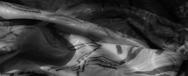 Soyut mürekkep desenli siyah ve beyaz katlanmış kumaş, organik şekiller ve ışık yansımaları ile dokulu bir sıvı oluşturur..