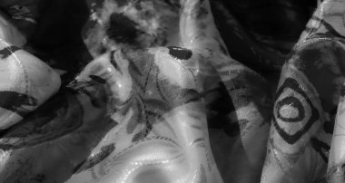 Yumuşak kumaşın soyut siyah ve beyaz desenli yakın çekimi, akıcılığı ve karmaşık tasarımları vurguluyor.