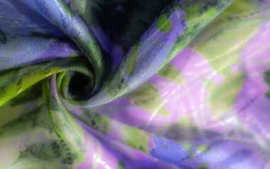 Yürekli, renkli desenli, canlı yeşiller ve mor renkli bir kumaş. Yumuşak kıvrımlarla örtülmüş, doku ve hareket yaratıyor..