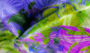 Soyut yeşil, mor ve mavi desenli, ipeksi desenli, parlak bir kumaşın yakın çekimi..