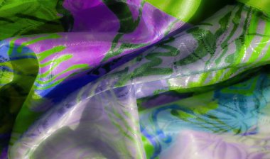 Soyut yeşil ve mor kıvrımlı parlak bir yüzeye sahip renkli bir kumaş. Işık karmaşık kıvrımları ve yansıtıcı dokuyu geliştirir, dinamik ve sanatsal bir tasarım yaratır..