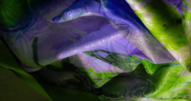 Pürüzsüz dokular ve koyu renk zıtlıkları gösteren, ipeksi kumaş üzerinde yeşil ve mor soyut desenlerin canlı bir yakın çekimi.