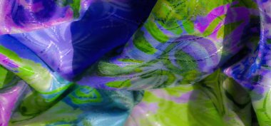 Canlı soyut kıvrımları ve şekilleri olan yeşil ve mor bir kumaş, gösterişli, sanatsal desenler ve ipeksi dokular için yumuşak bir örtü..