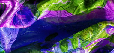 Yumuşak desenler ve ışık yansımalarının karışımını geliştiren, yeşil, mor ve sarı tonlarıyla kumaşın soyut bir karışımı.