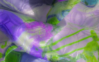 Parlak yeşil ve mor soyut kumaştan oluşan, ipeksi bir dokusu ve yumuşak ışıklandırması olan, kumaşın karmaşık dokusunu aydınlatan bir yakın çekim..