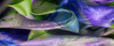 Yumuşak akan kumaşla yeşil, mor ve mavi renklerin karışımı ışık ve gölge oyunlarının soyut bir görüntüsünü oluşturuyor..