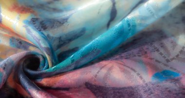 Canlı, soyut, mavi, sarı ve turuncu renkli kumaş, özenle toplanmış, pürüzsüz, akıcı dokusu ve sanatsal tasarımı sergiliyor..