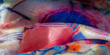 Sarı, kırmızı, mavi ve mor tonlarında koyu renk lekeleri olan parlak, canlı, soyut kumaş. Yumuşak parıltı ve karmaşık tekstil kıvrımları dinamik bir sanatsal görünüş yaratır..