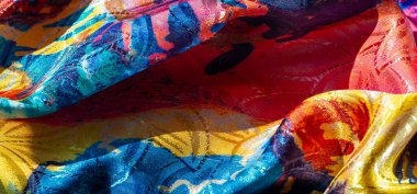 Renkli ve soyut desenleri olan yumuşak, dalgalı bir kumaş, yumuşak pasteller ve daha derin renkler harmanlanmış. Yüzey ışığı yakalar, dinamik ve akışkan bir etki yaratır..